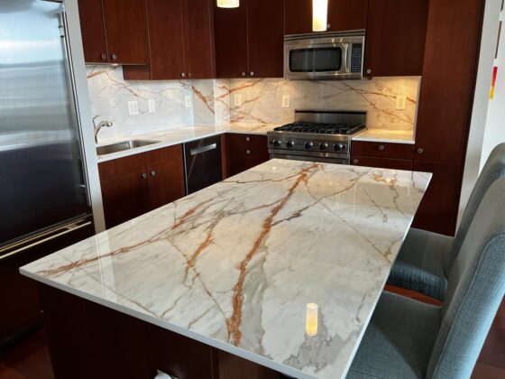 Modern kitchen with marble-style quartz island countertop, matching backsplash, and dark wood cabinetry