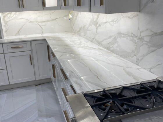 white marble kitchen countertop and full slab backsplash with gray veining modern cabinets and gas cooktop