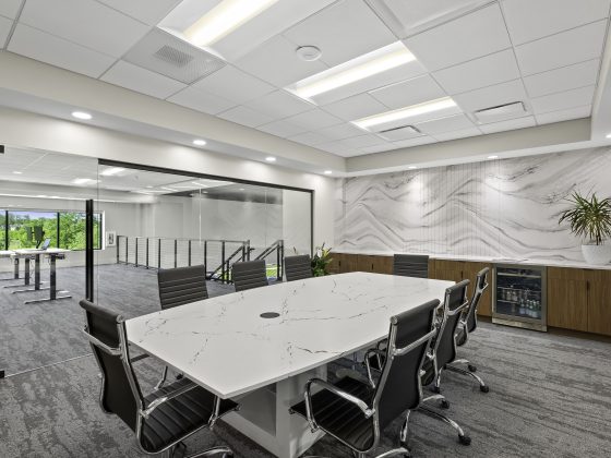 Modern conference room with quartz meeting table, glass partition wall, and stone feature wall inside a contemporary design studio
