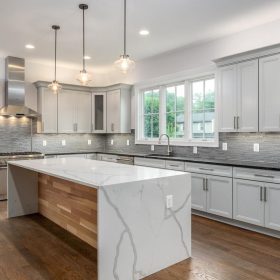 modern kitchen with calacatta quartz waterfall island white cabinets and contemporary tile backsplash