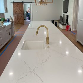 modern kitchen island with calacatta quartz countertop and brass faucet in luxury kitchen interior