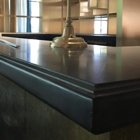 modern bar counter with dark stone countertop and decorative edge profile in luxury interior setting