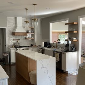 modern kitchen with waterfall quartz island countertop white cabinets and brass pendant lighting