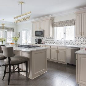 modern luxury kitchen with marble island countertop white cabinets and geometric tile backsplash