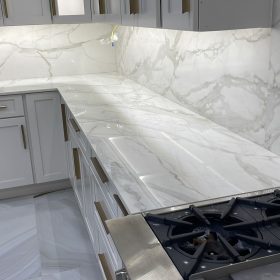 modern kitchen with calacatta marble countertop and full height marble backsplash with white shaker cabinets