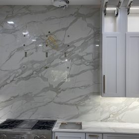 modern kitchen with full height calacatta marble backsplash and white shaker cabinets