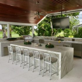 outdoor kitchen with marble countertop island, bar seating, built-in grill and covered patio entertainment area