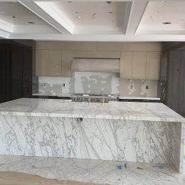 large waterfall marble kitchen island with dramatic gray veining in luxury kitchen under construction