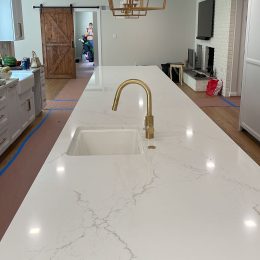 modern kitchen island with white quartz countertop gold faucet pendant lighting and contemporary cabinetry
