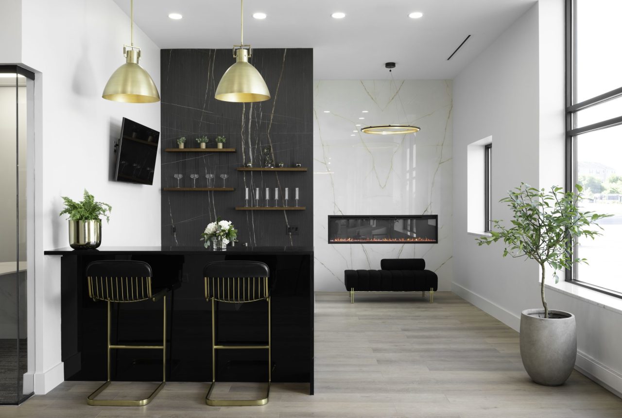 Modern lounge and bar area with stone feature wall, pendant lighting, fireplace, and luxury seating in a contemporary design studio